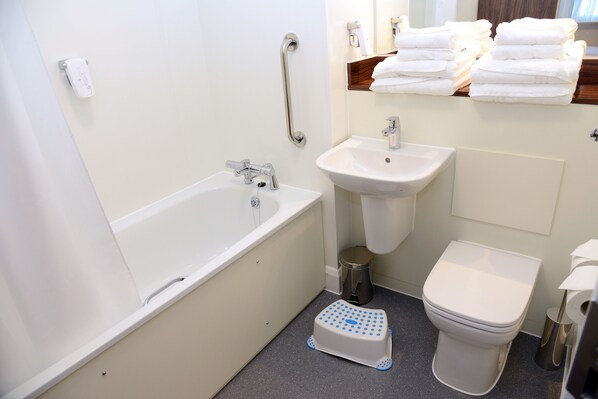 A bathroom with a bathtub, sink, toilet, and a step stool.