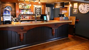 A bar area with a wooden counter, a clock, and a sign offering 2 bottles for £5. - Woodcocks, Lincoln by Marston's Inns (Lincoln)