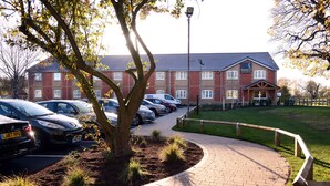 A brick building with a parking lot and a paved walkway. - Woodcocks, Lincoln by Marston's Inns (Lincoln)