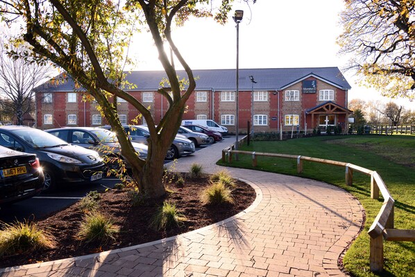 A brick building with a parking lot and a paved walkway.