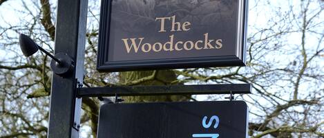 «The Woodcocks» -nimisen pubin kyltti, jossa on lintukuva ja tunnuslause: «Syö hyvin. Nuku hyvin».