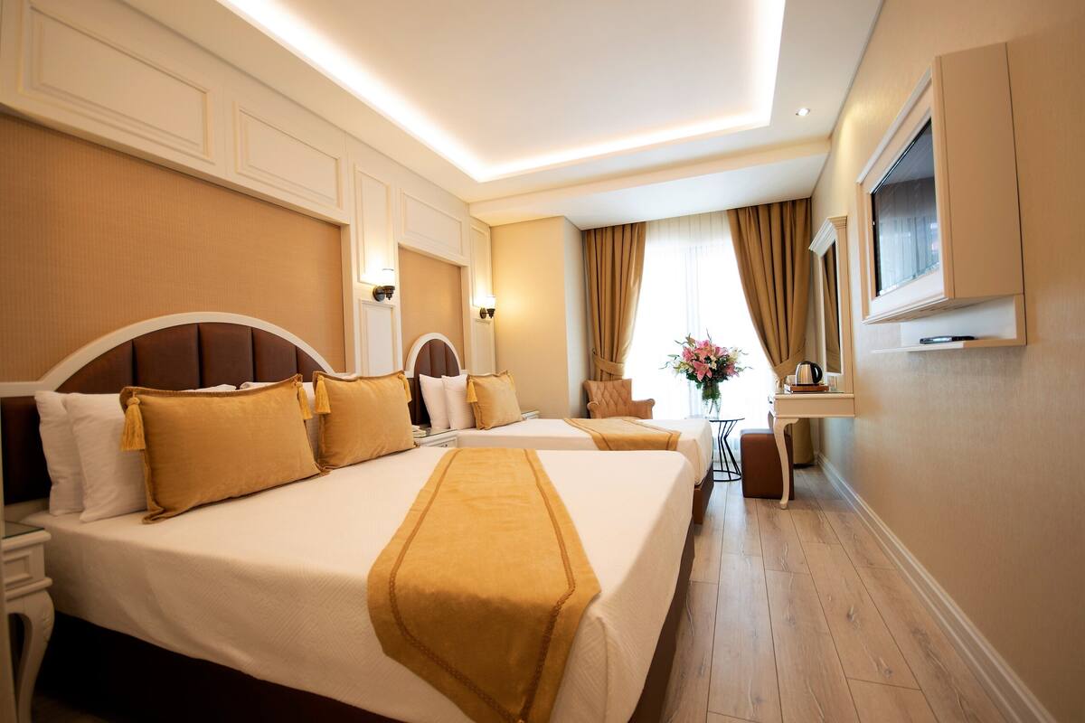 A hotel room with two large beds, a desk, and a television mounted on the wall.