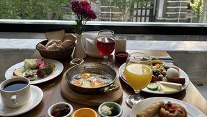 A breakfast table with various food items and a view of a building with a gothic arch. - Boss Hotel Sultanahmet (Istanbul)