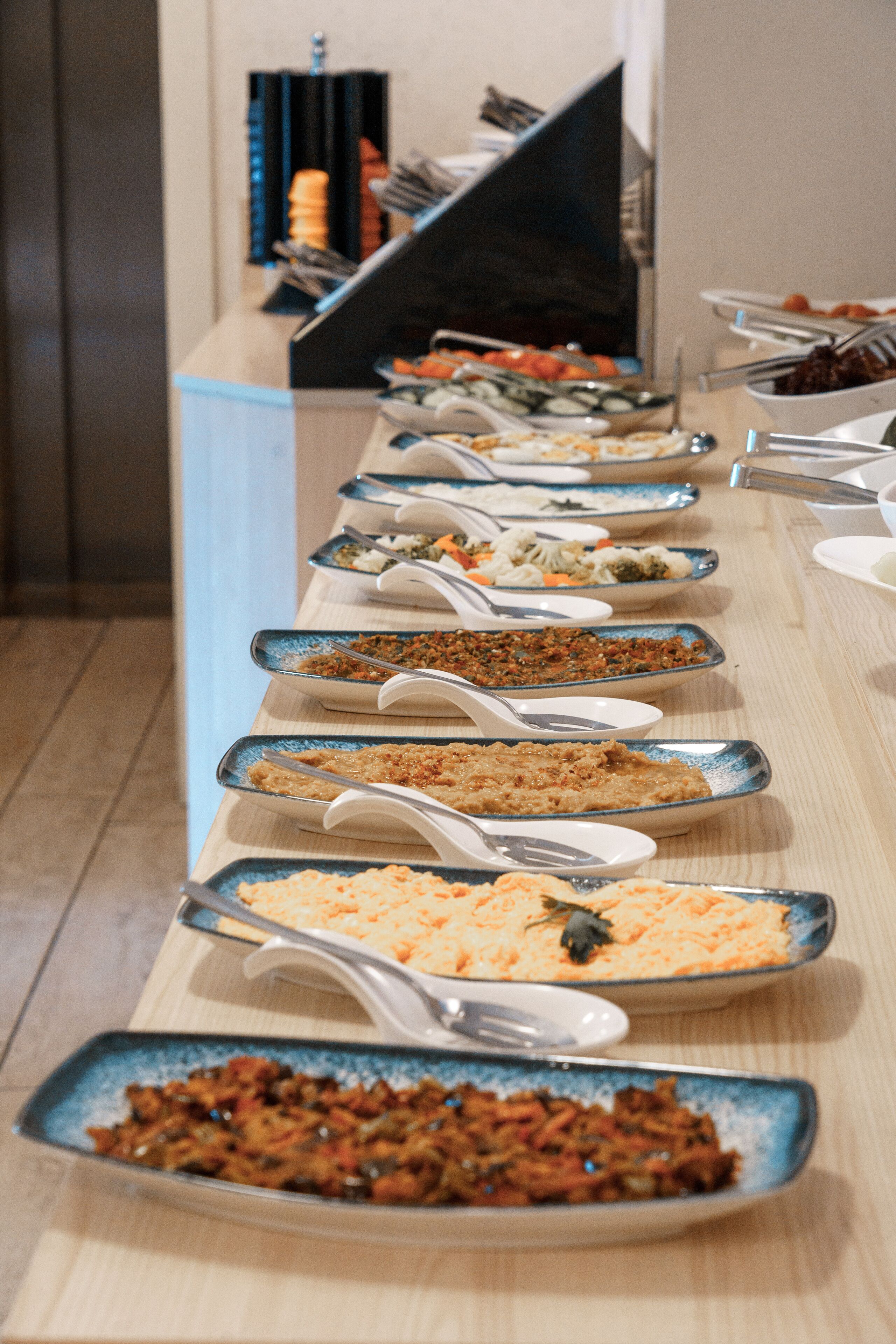 A buffet table with various dishes and serving utensils.