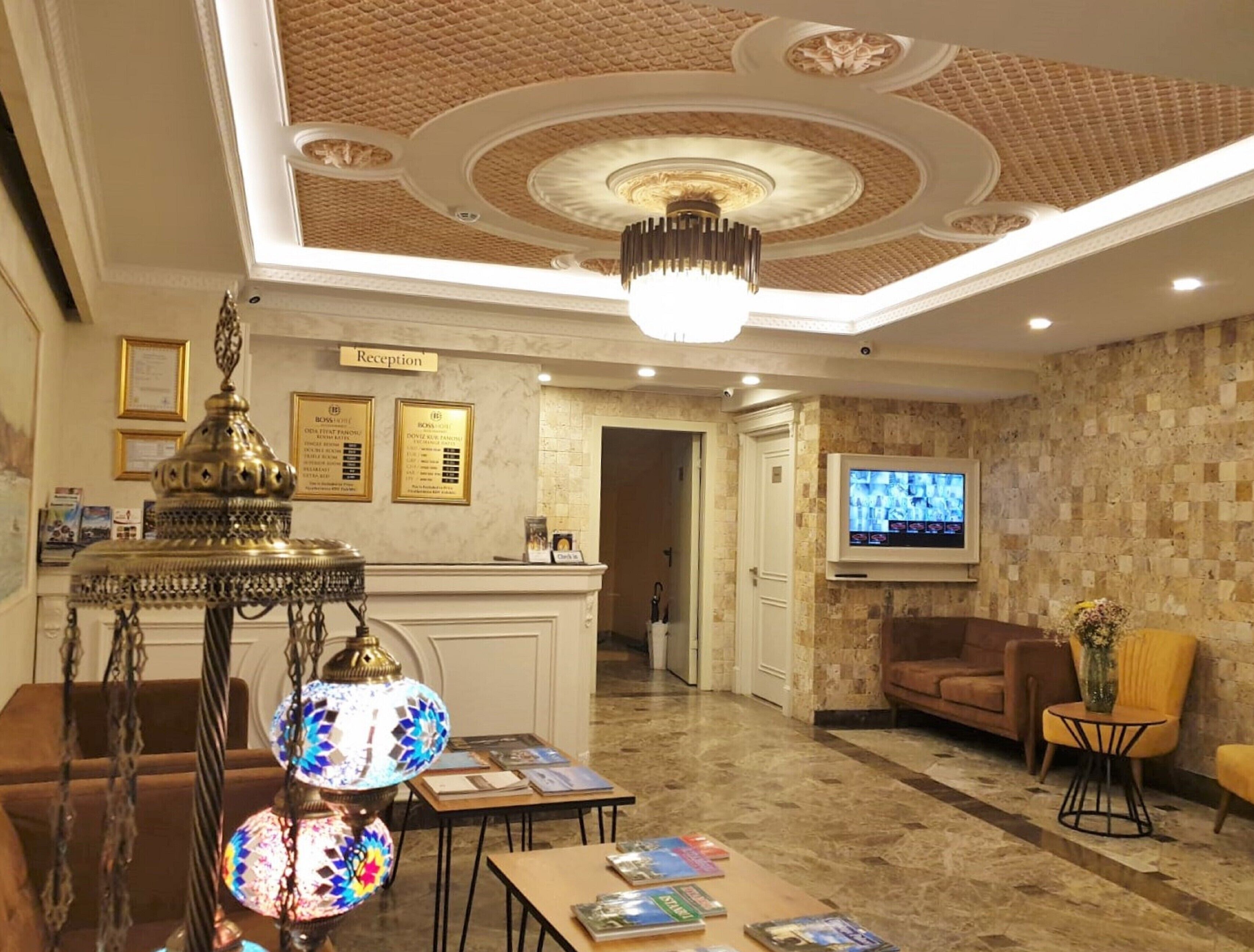 A lobby with a reception desk, a chandelier, a television, and a sofa.