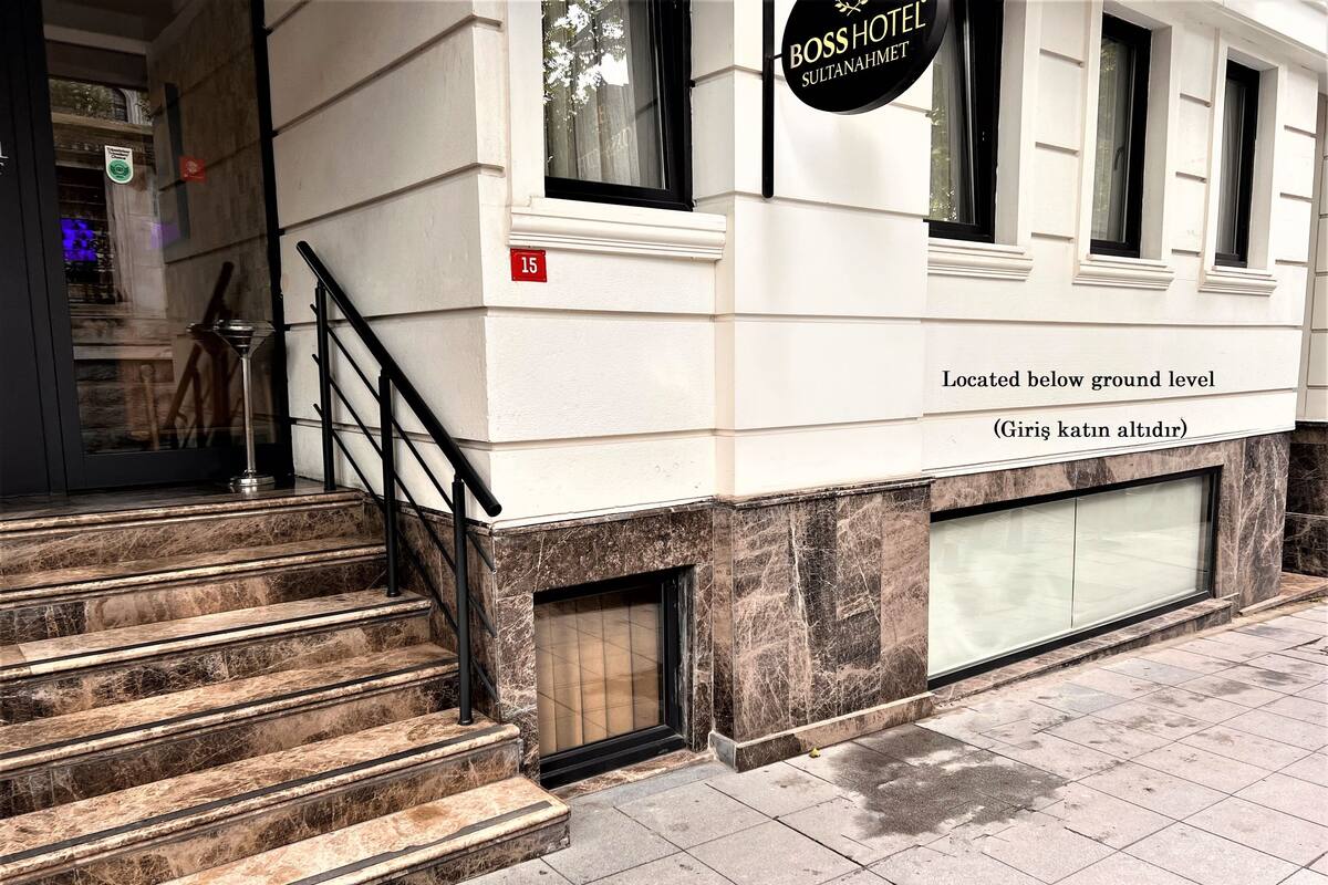 A hotel entrance with marble steps, a black metal railing, and a sign indicating the location below ground level.