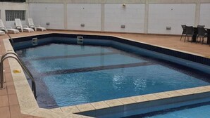 An indoor swimming pool with clear water, tiled edges, and lounge chairs around the perimeter. - Koza Town (Lagos)