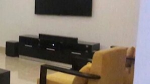 A modern living room with a flat-screen TV mounted on the wall, a black entertainment unit, and a yellow armchair. - Koza Town (Lagos)