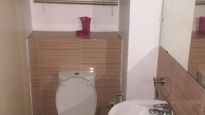 A small bathroom with a toilet, sink, and window with blinds. - Koza Town (Lagos)