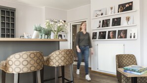 A modern living room with a sofa, two chairs, a coffee table, a bookshelf, and a wall with framed photos. - Kunst-Hotel Drei König am Marktplatz Stadt Lörrach (Loerrach)