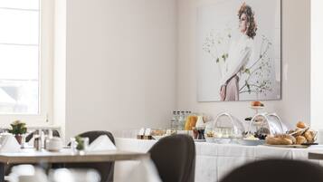 Une table dressée pour le petit-déjeuner, avec des chaises et une variété d’aliments et de boissons.