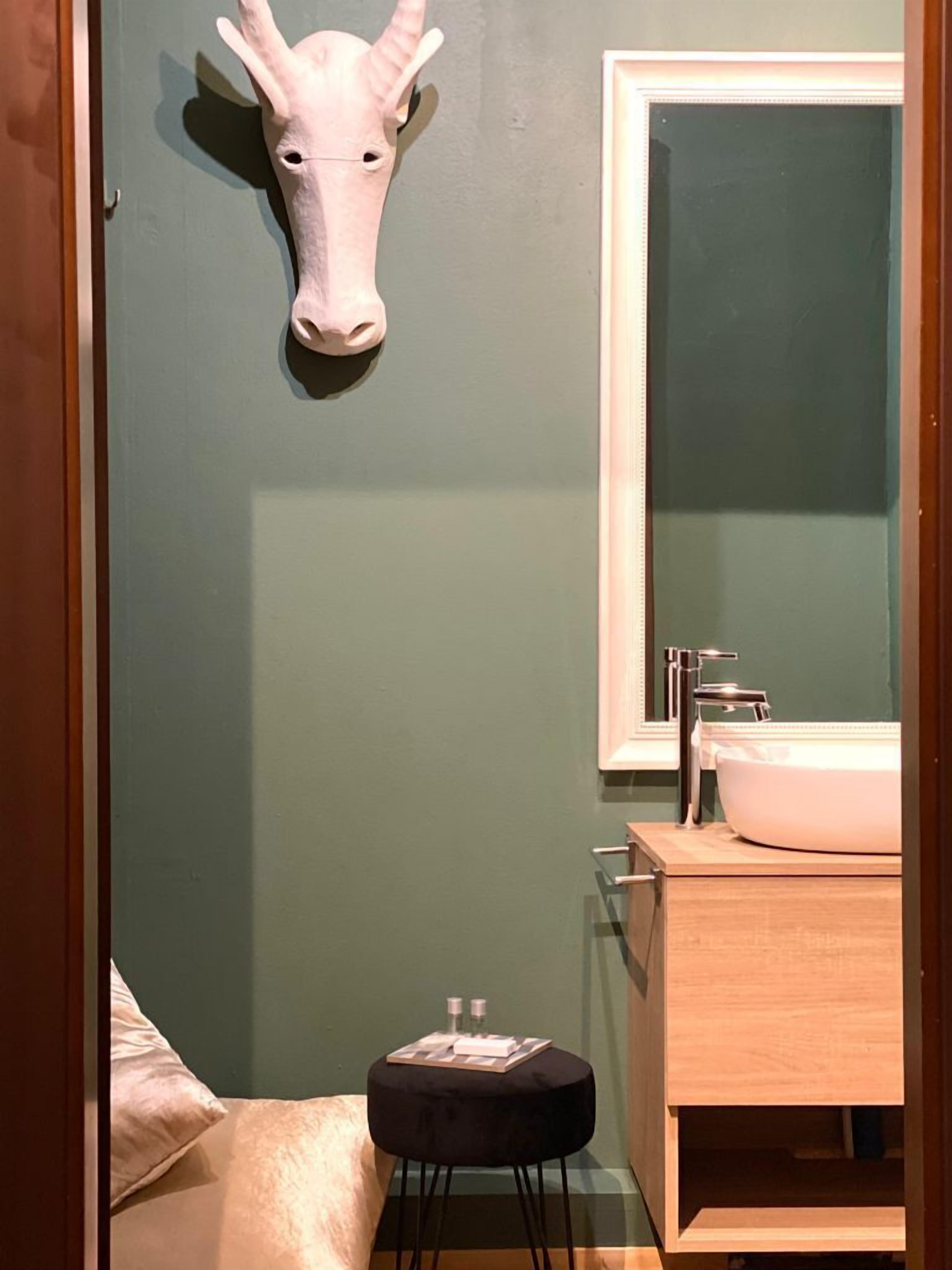 A bathroom with a green wall, a white sink, and a mirror.