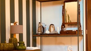 Una habitación con una cama litera, un escritorio con lámpara, una cafetera, un hervidor y un flamenco decorativo.