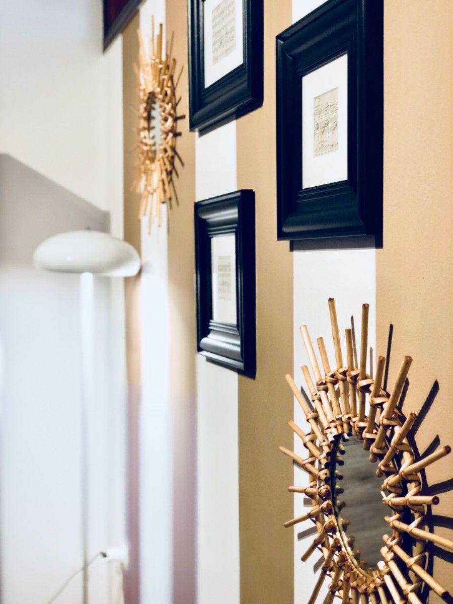 Un pasillo con obras de arte enmarcadas en la pared y una escultura original montada en la pared.
