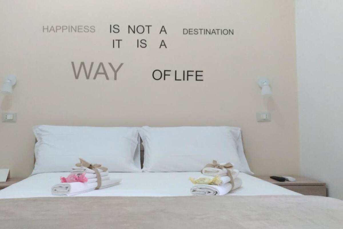 Habitación de hotel con cama, almohadas y una cita motivacional en la pared.