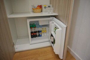 Un refrigerador compacto con compartimento congelador, lleno de bebidas y aderezos.