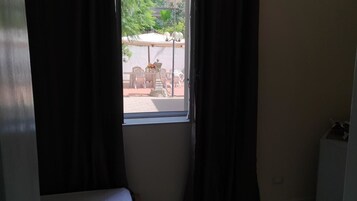 Una habitación con ventana que da a un área de estar exterior con mesas y sillas.