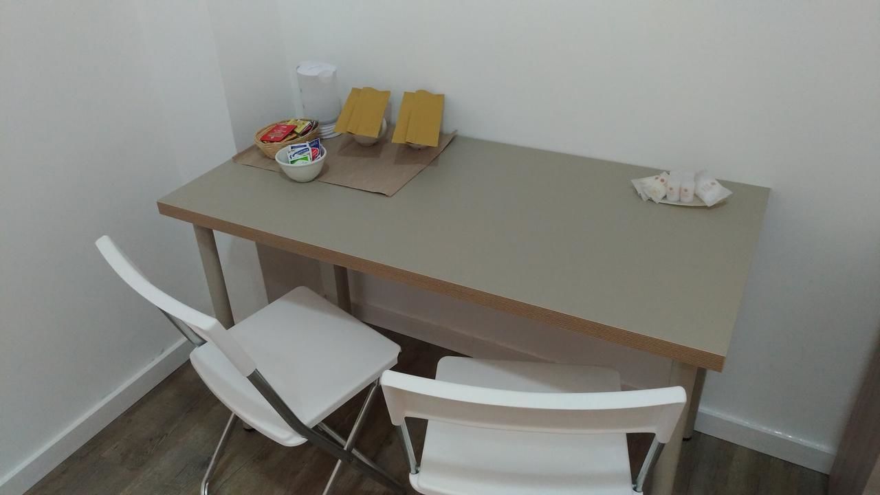 A small dining area with a table, two white chairs, a bowl of snacks, and some napkins on the table.