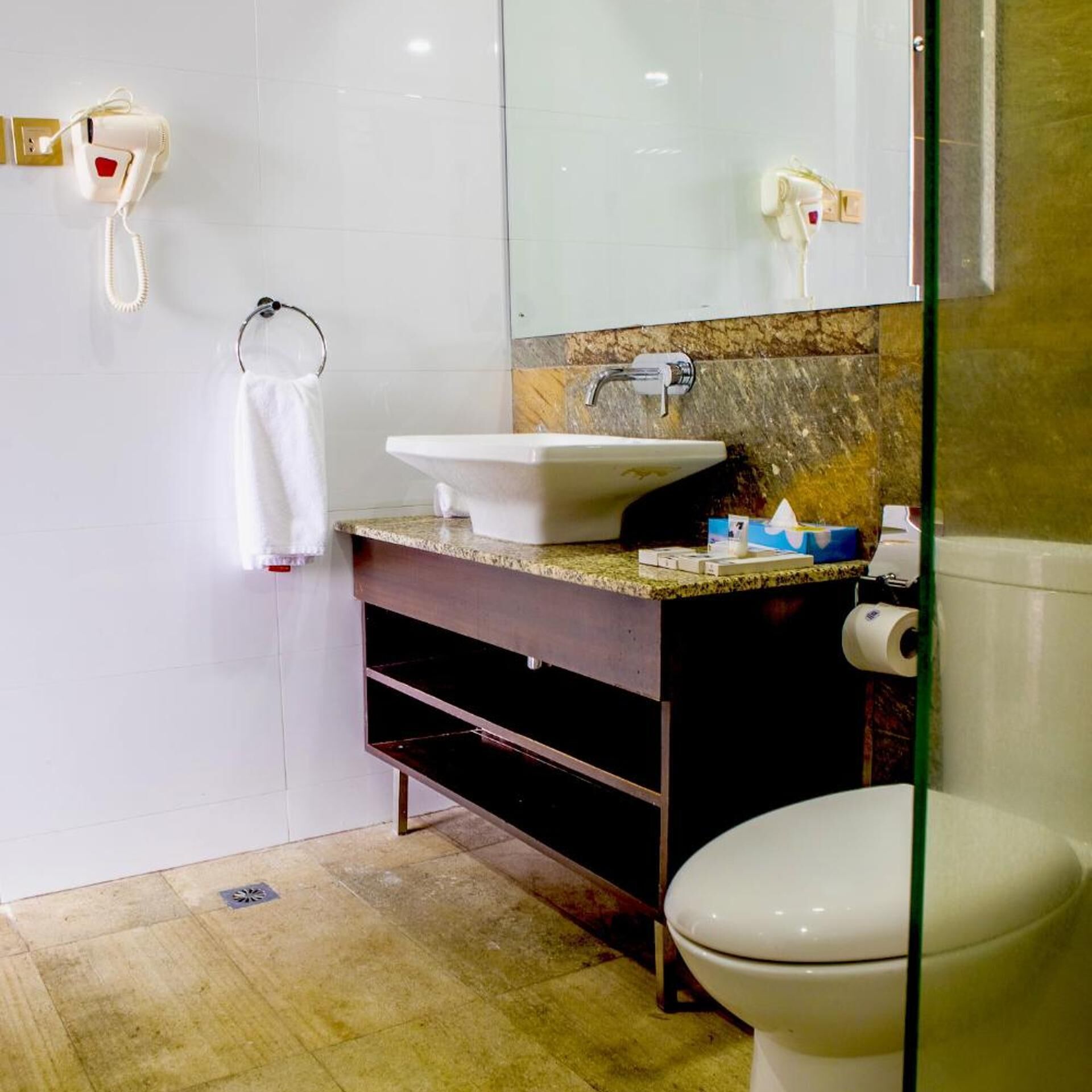 Ein Badezimmer mit Waschbecken, Spiegel, Handtuchhalter und Toilette.