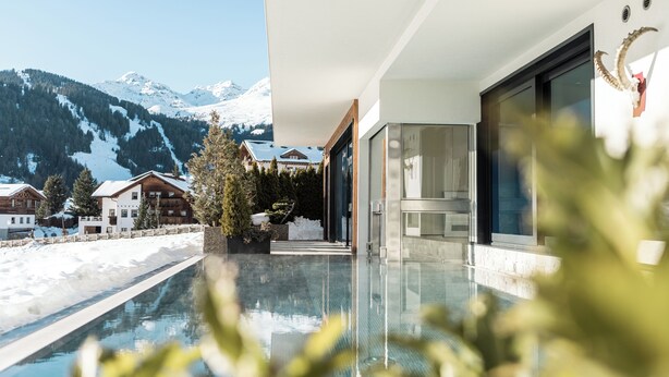 Un área de piscina moderna con vistas despejadas a montañas nevadas al fondo.