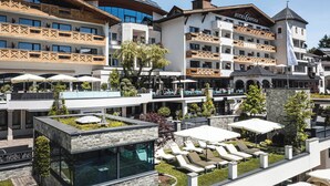 Un hotel con varios balcones, mobiliario exterior y zona de piscina.