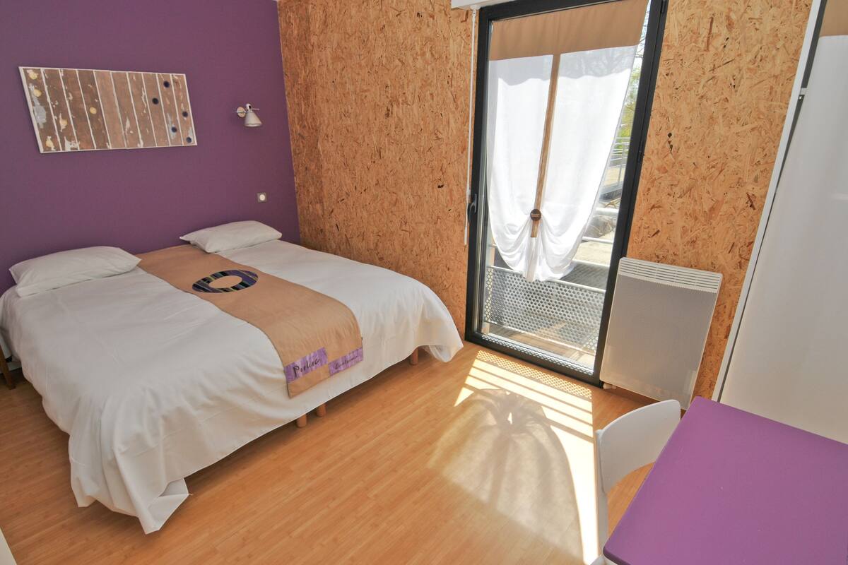 Une chambre à coucher avec un lit, une table et une fenêtre avec des rideaux.