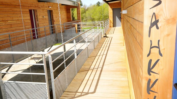 A wooden deck with a metal railing, a wooden wall with the number "2" and the word "SAHKKU" on it, and a metal roof above. - Auberge Des VoyaJoueurs (Monteneuf)