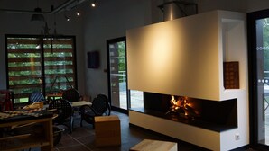 A modern interior with a fireplace, seating area, and large windows. - Auberge Des VoyaJoueurs (Monteneuf)