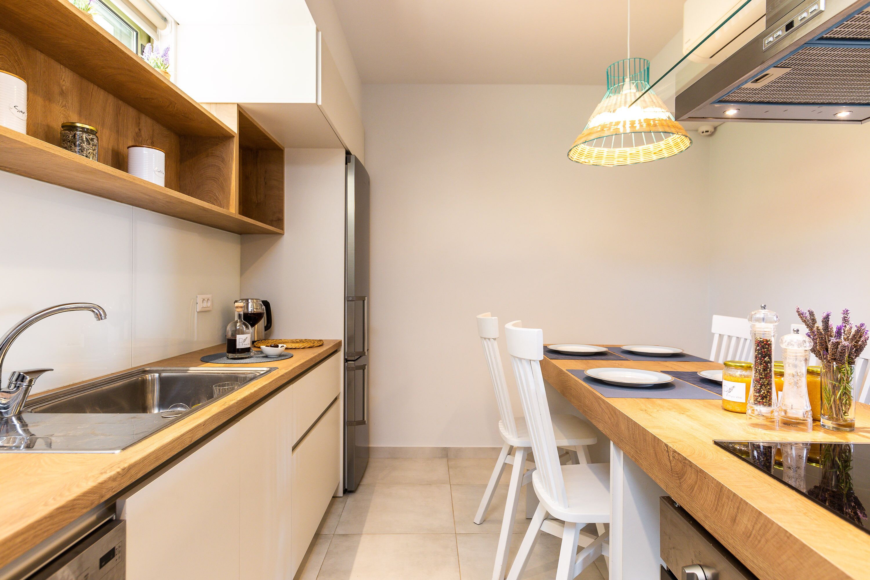 Une cuisine moderne avec des plans de travail en bois, un évier en acier inoxydable et des chaises blanches.