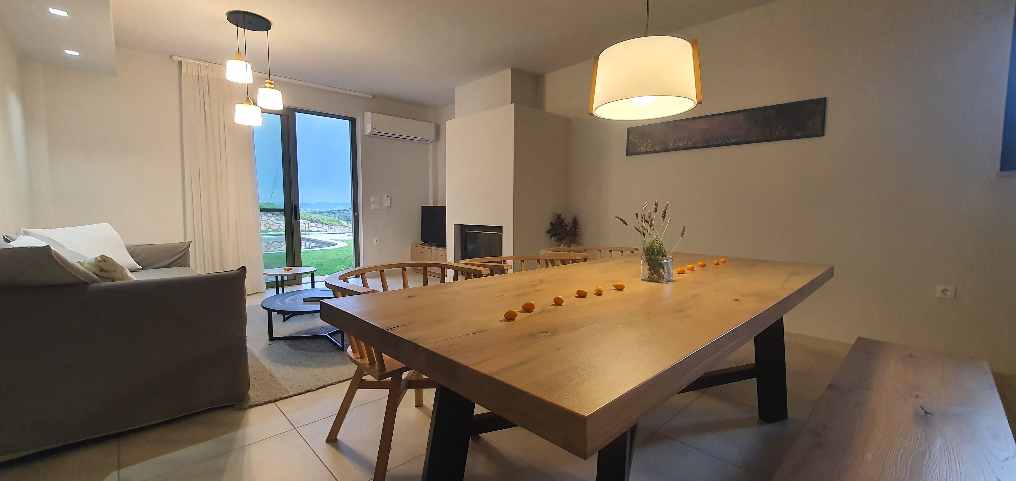 A modern living room with a wooden dining table, a sofa, and a TV.