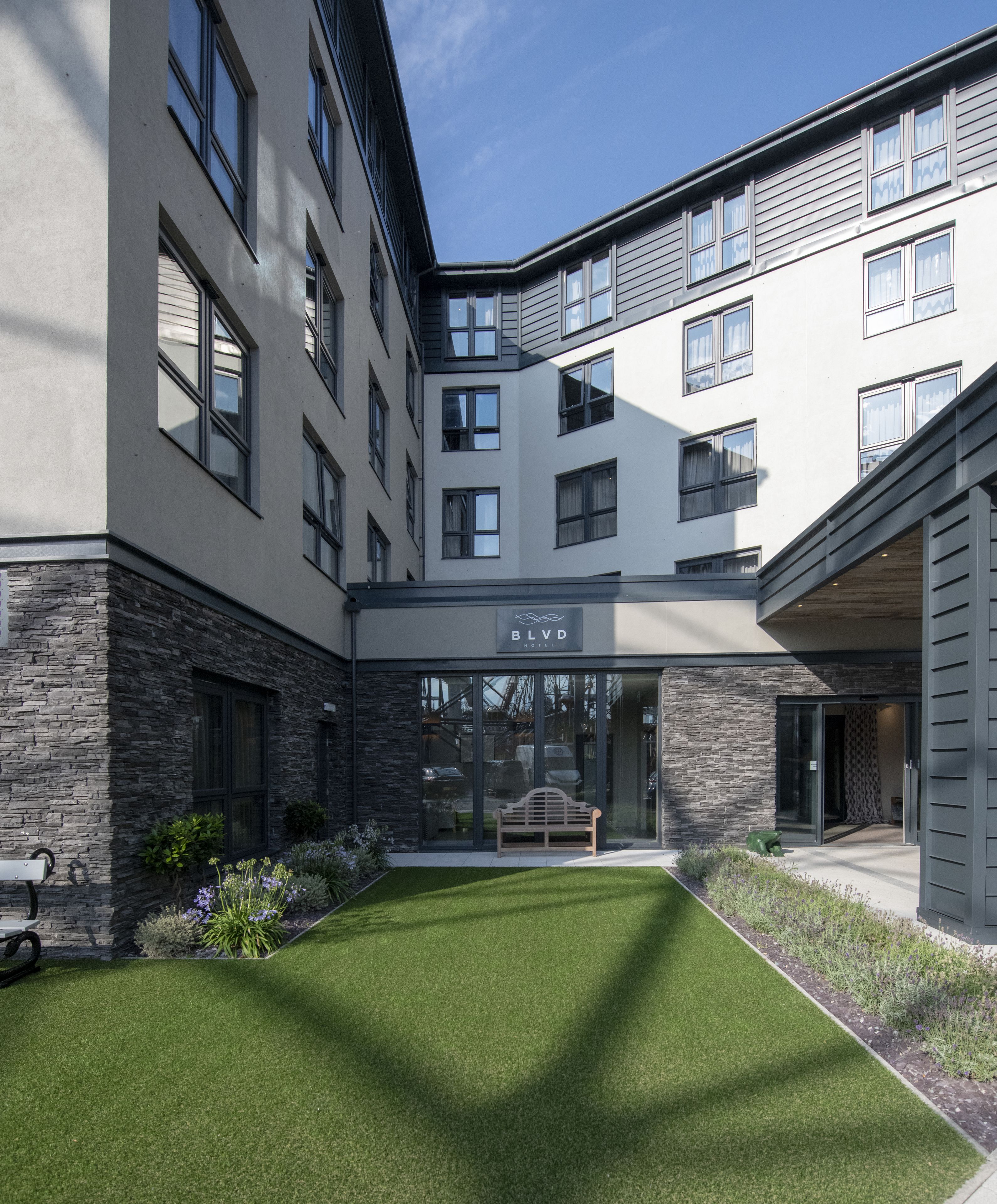 A modern hotel with a courtyard, stone facade, and a sign reading "BLVD HOTEL".