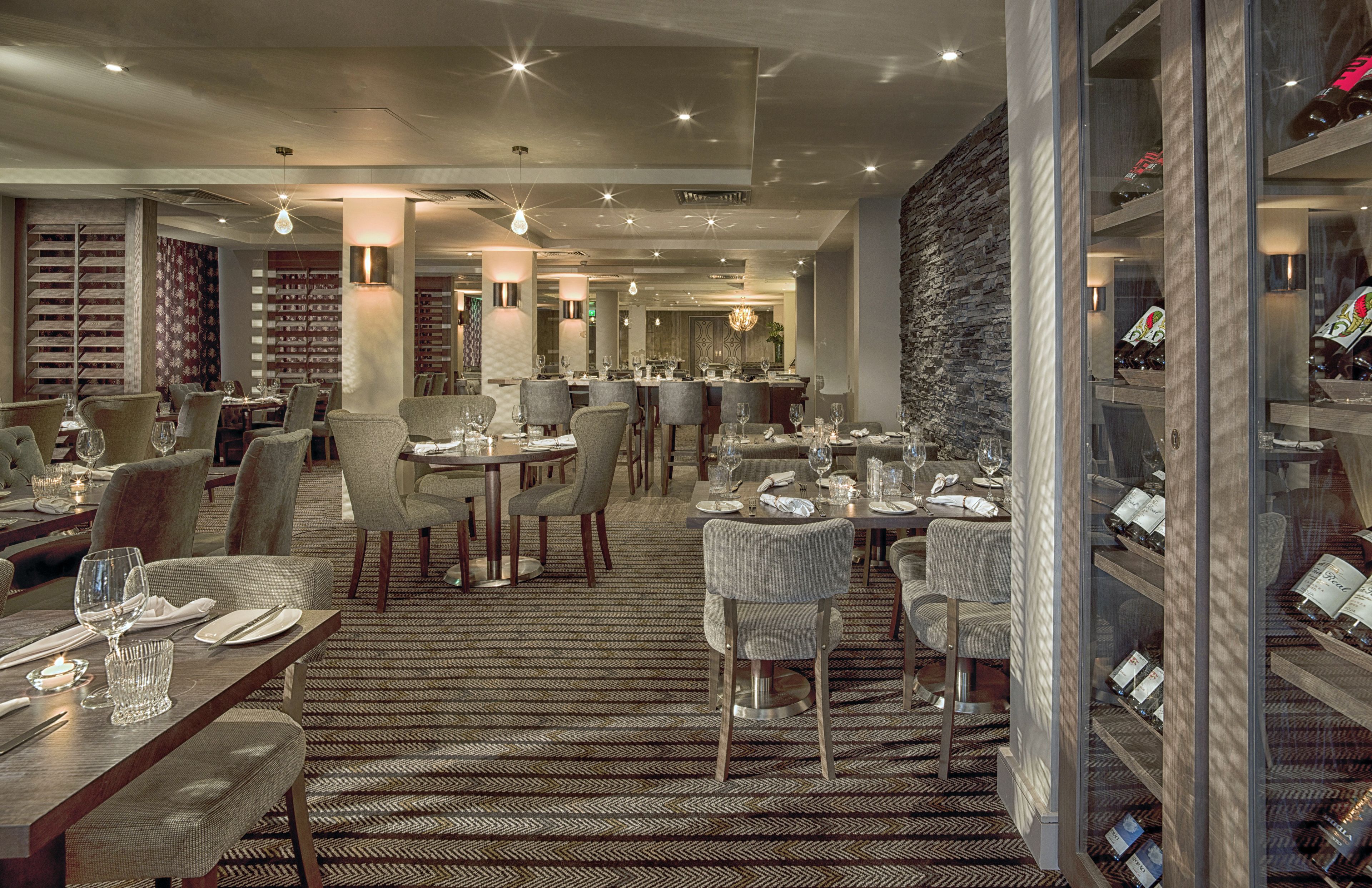 Een modern restaurant met meerdere eettafels en stoelen, een kamerbreed tapijt met patroon en een wijnrek.