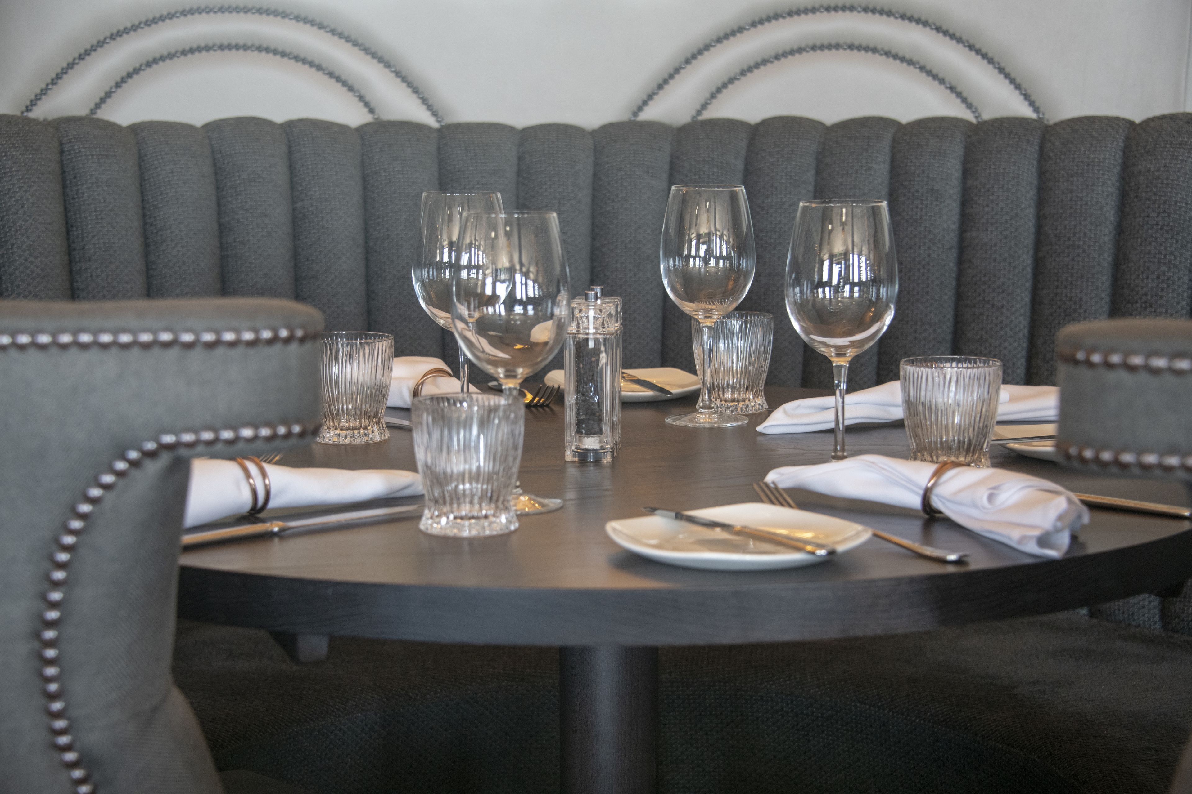 A dining table set with multiple wine glasses, a salt and pepper shaker, and neatly folded napkins.