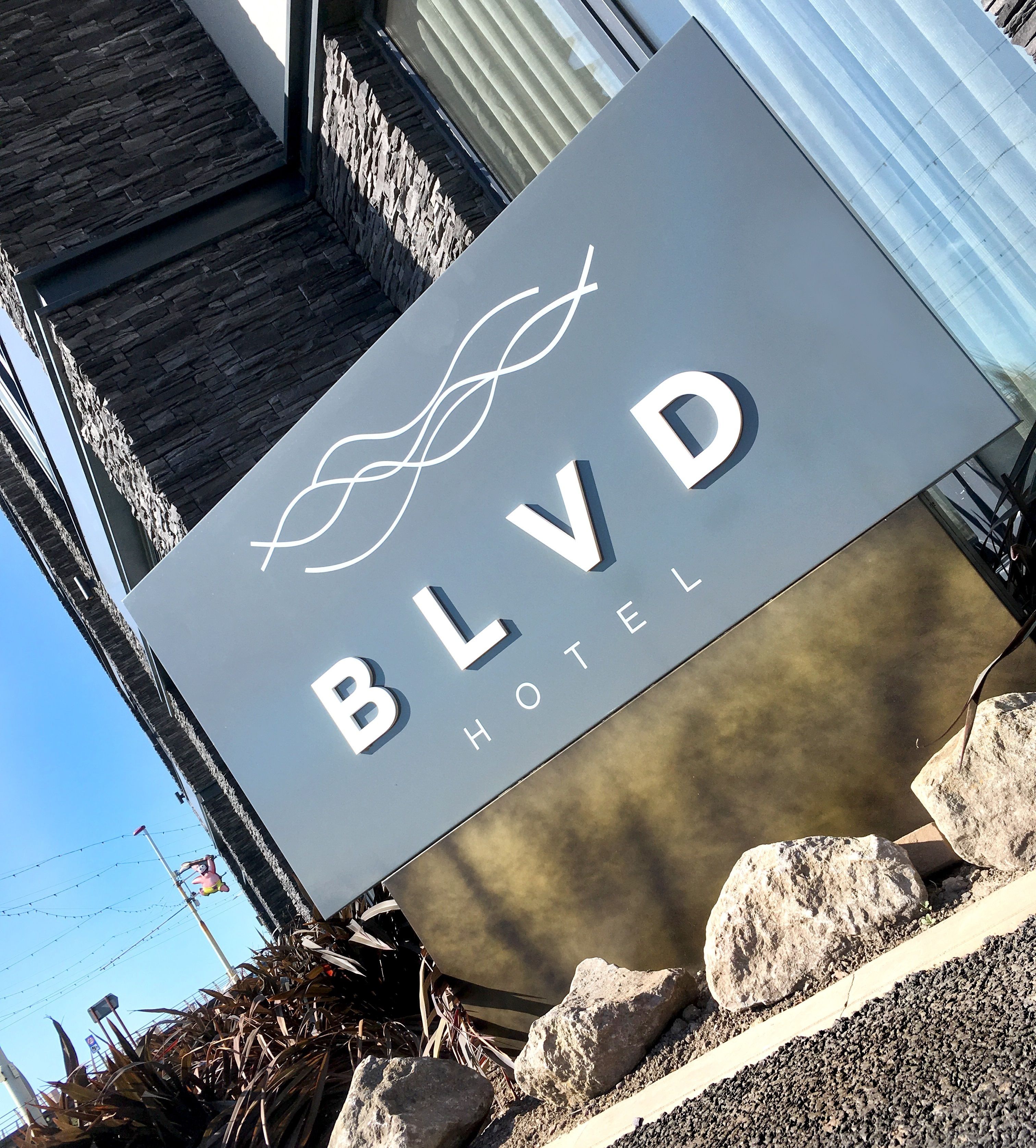 A sign for the BLVD Hotel with a modern design and a wave-like logo.