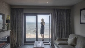 A room with a large sliding glass door leading to a balcony with a view of the sea. There is a sofa and a small table in the room. - Boulevard Hotel (Blackpool)