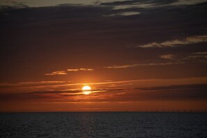 A sunset over a calm sea with a distant horizon line.