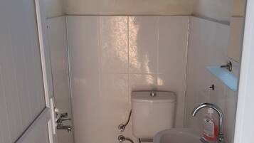 Un baño pequeño y limpio con inodoro, lavabo y ducha.