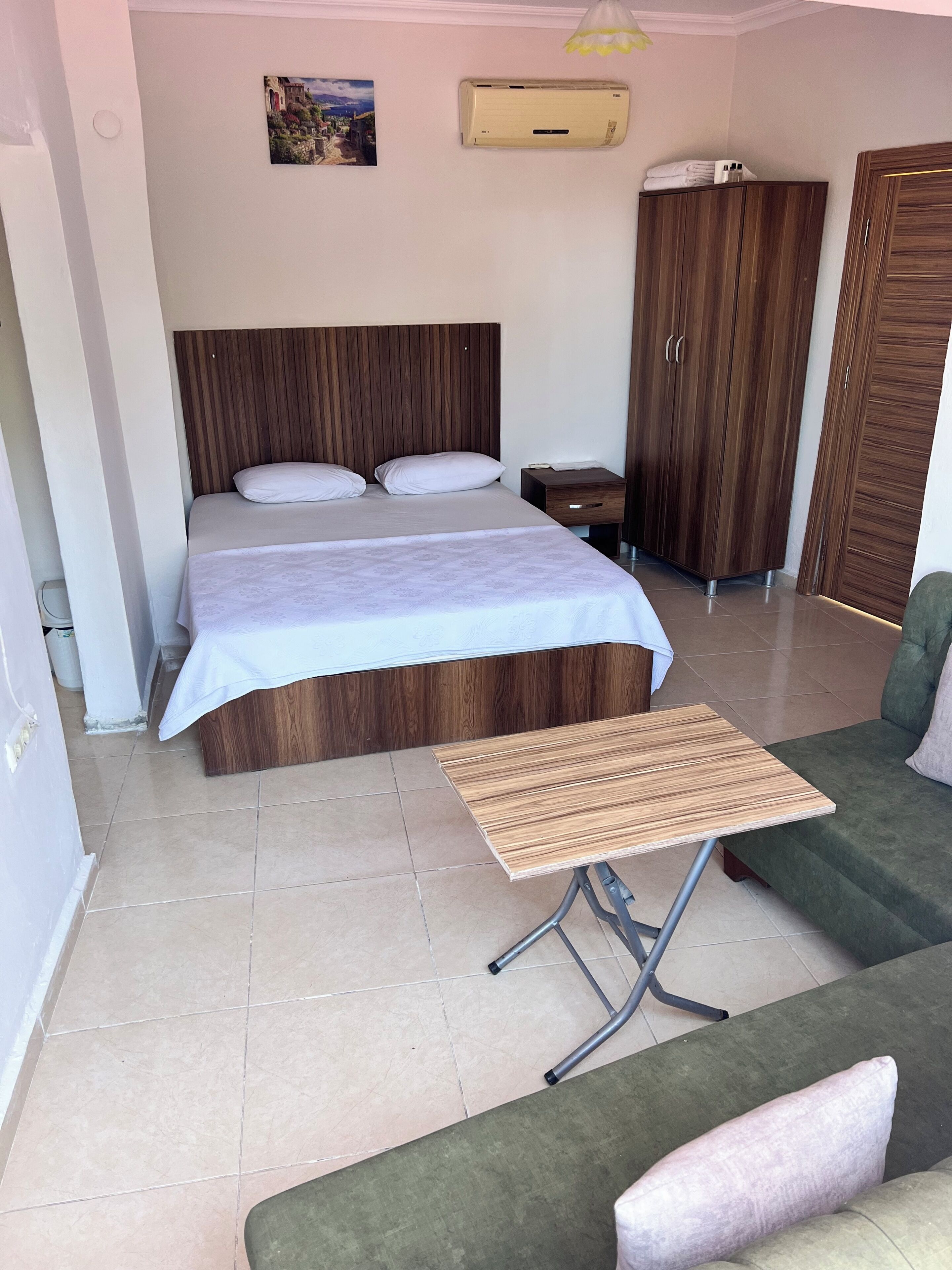 Ein Schlafzimmer mit einem Bett, einem Nachttisch, einem Kleiderschrank und einem grünen Sofa.