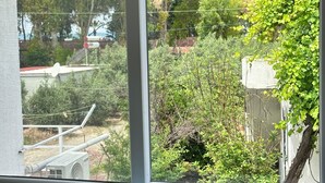 Una habitación con ventana que da a un jardín y vistas de árboles y un edificio.
