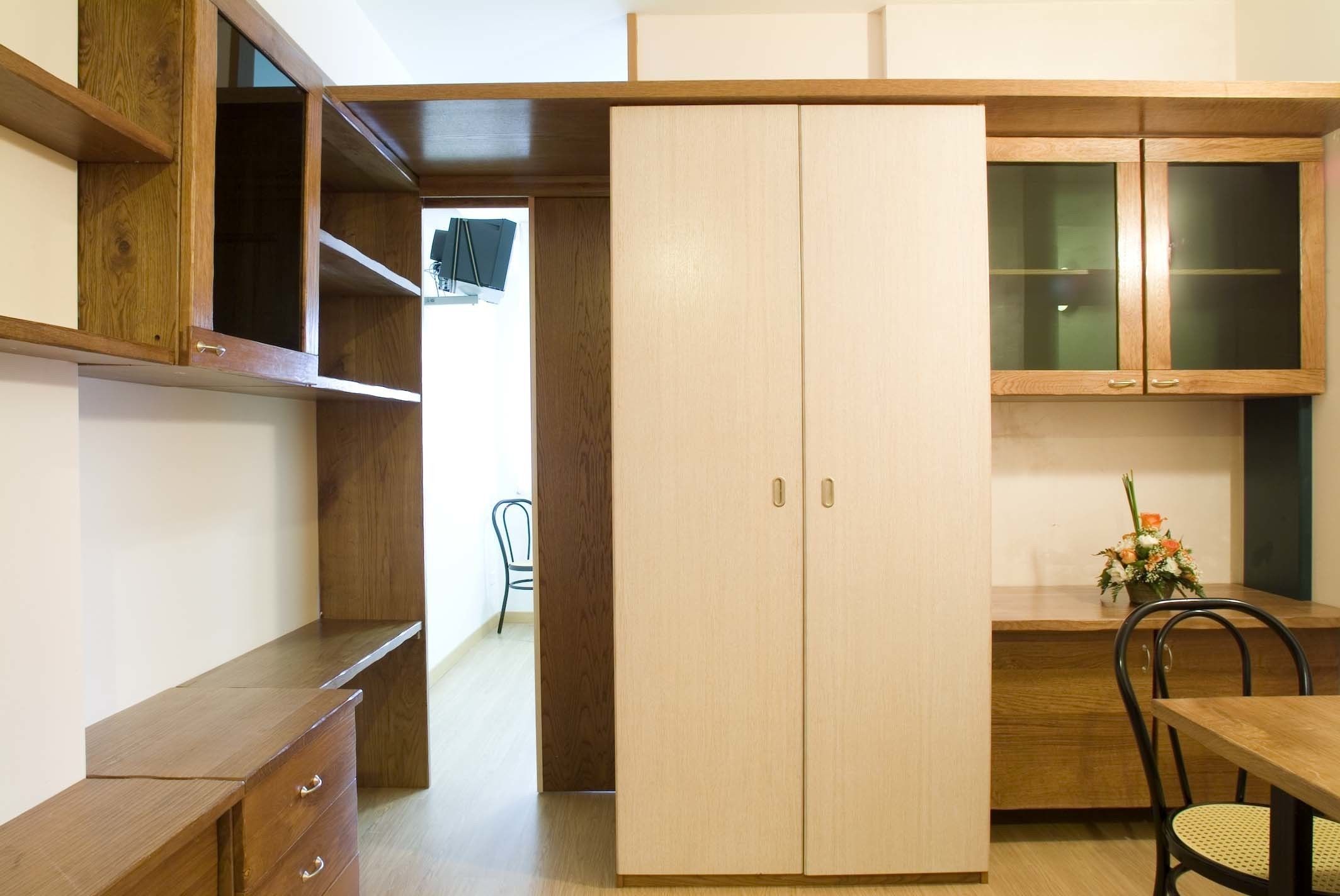 A compact kitchen with wooden cabinets, a built-in bench, and a dining area with a table and chairs.