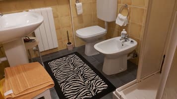 Un bagno con lavandino, WC, bidet e un tappeto a motivi zebrati.