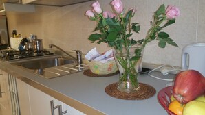 A kitchen with a sink, stove, and a vase with pink roses on the counter. - B&B Le Terrazze Boutique Hotel 2 Torino (Cirie)