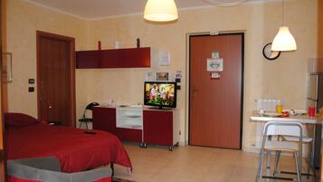 Une chambre d’hôtel avec un lit, un bureau et une chaise, une télévision et une horloge au mur.
