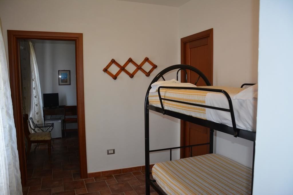 Quarto com cama de solteiro, mesa e cadeira.