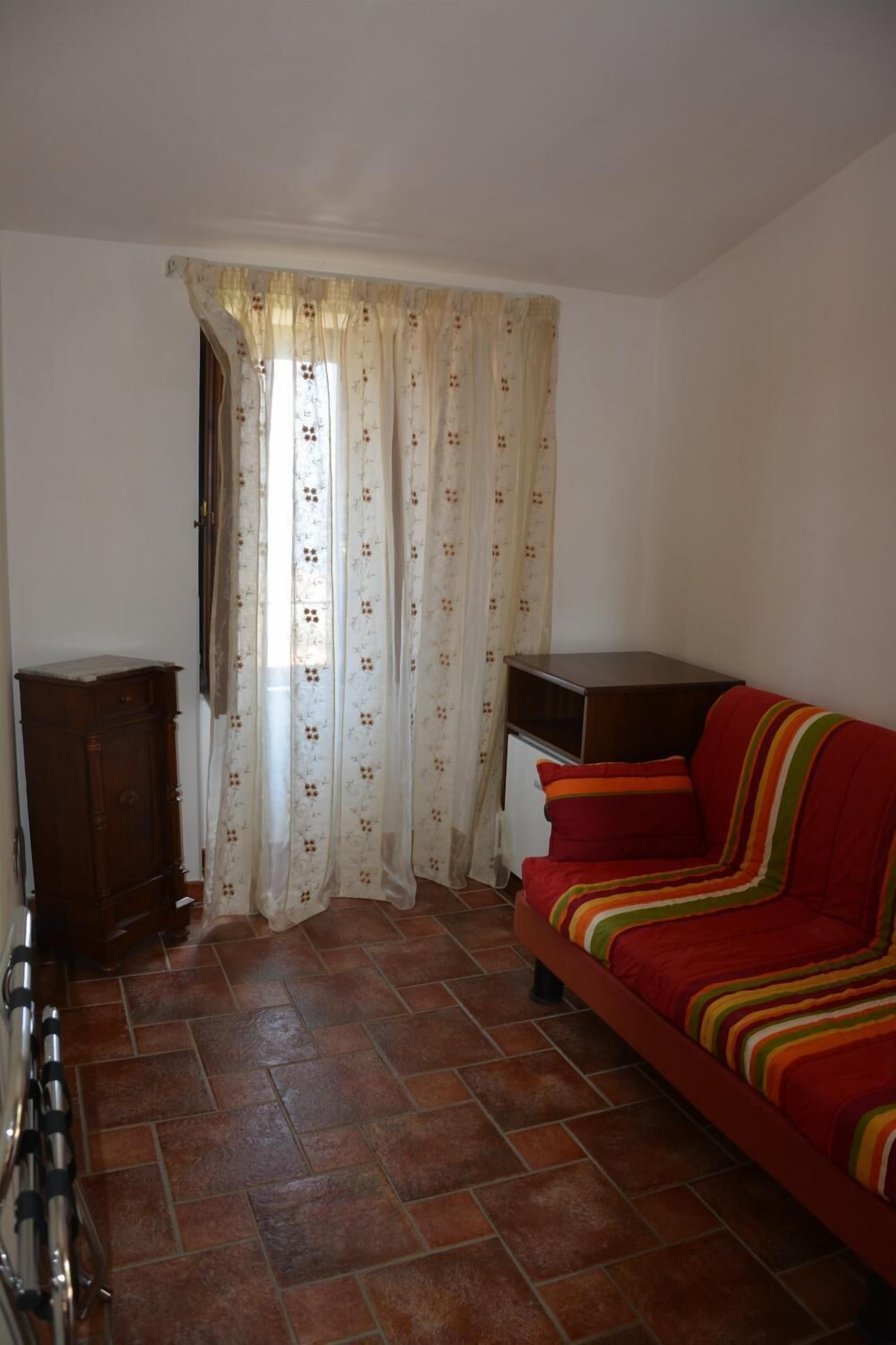 Una habitación con un sofá, un armario y una cortina.