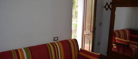 Una habitación con un sofá rojo, un aparador de madera y una puerta que da al exterior.