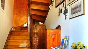 Un escalier en bois, sur lequel est posée une console blanche ornée de magazines et d’un vase de fleurs.