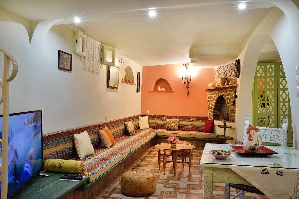 Un salon avec un canapé, un téléviseur, une table sur laquelle se trouve un saladier, et un coq décoratif.