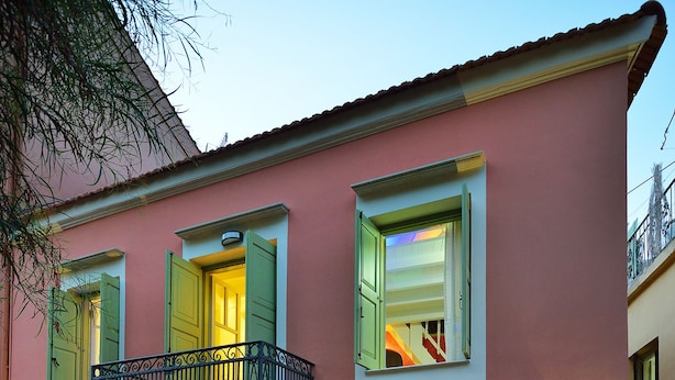 Un bâtiment rose doté d’un balcon, d’un escalier et d’une enseigne indiquant l’adresse.