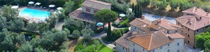 An aerial view of a property with a swimming pool, multiple buildings with tiled roofs, and surrounding greenery. - Podere Jana (Vinci)